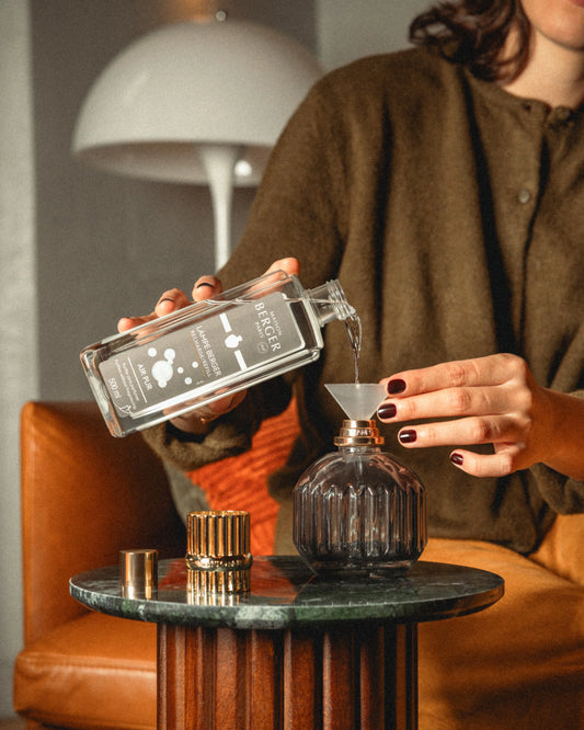 Person pouring lampe berger refill into the maison berger cannelo lamp. 